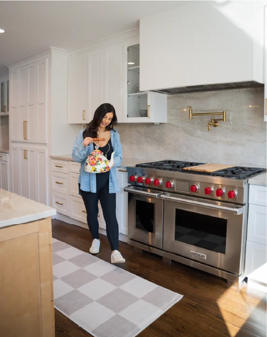 Tara standing in a bright kitchen holding a patterned tote